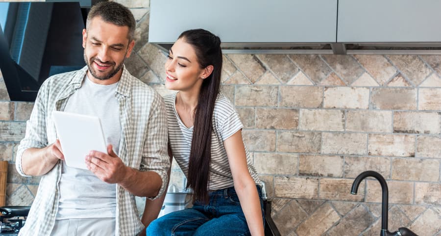 Young homeowners using a tablet together in the kitchen to run smart home